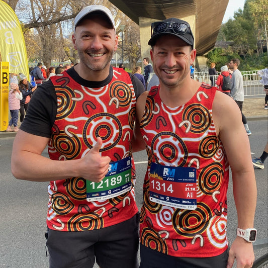 Red Dust runners wearing running singlet featuring artwork 'Walking Forward Together' created especially for Red Dust by Raymond Walters Penangke